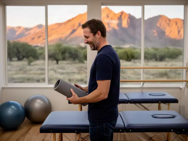 A therapist standing between padded treatment tables in a bright clinic.